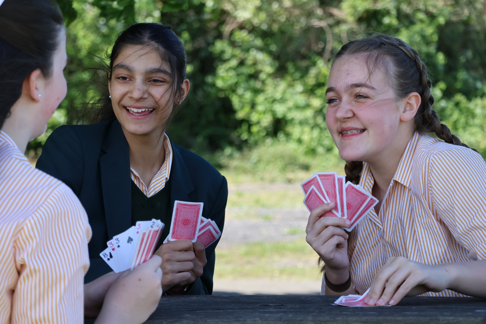 Students sitting at picnic table on our school field smiling and chatting