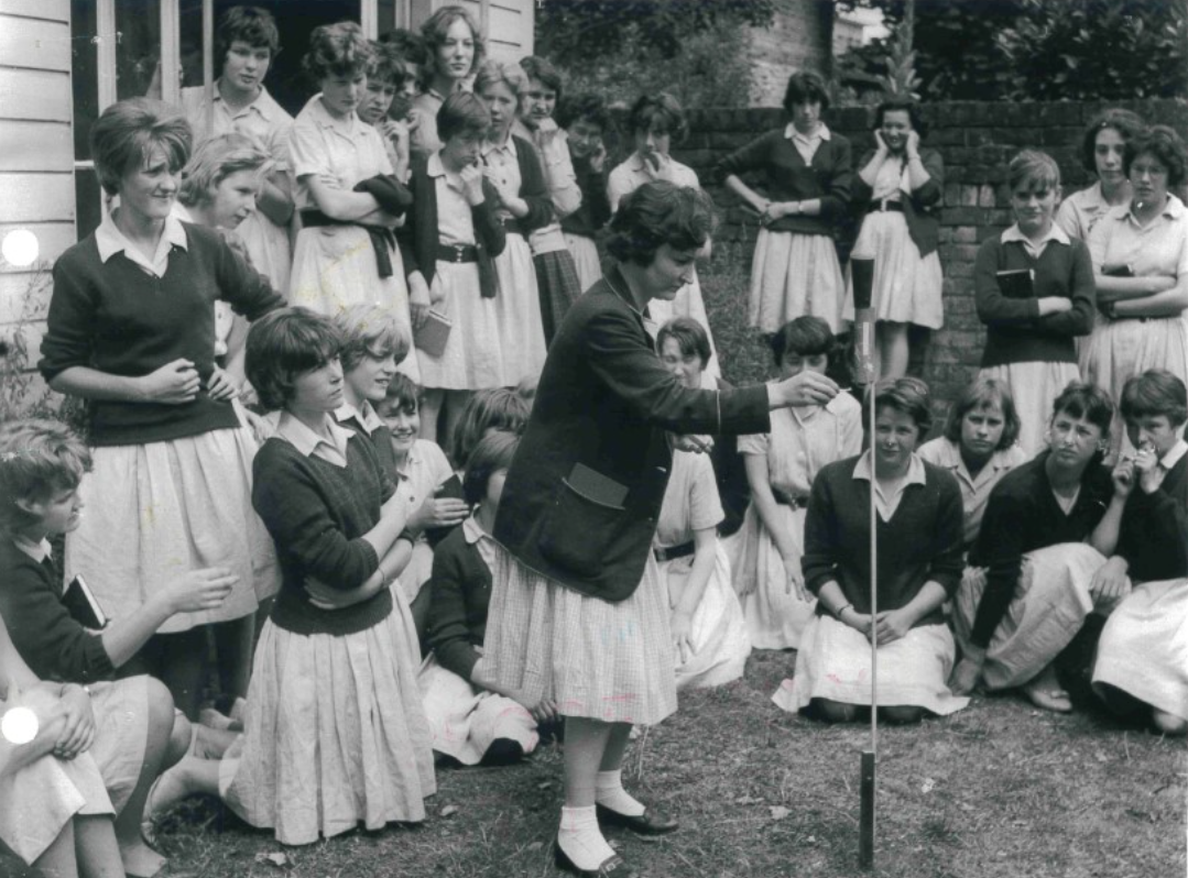 Black and white photo of Ribston students sitting and standing a the garden