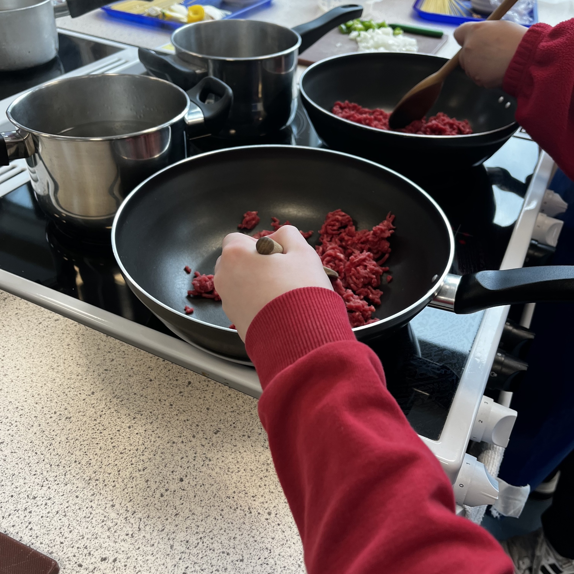 A primary school child frying some mince in a cooking lesson